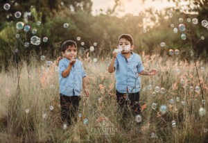 Family Session - little boys standing in a grassy field at sunset blowing bubbles