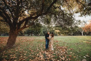 Baby photography - A family cuddle their baby girl under an autumn coloured tree