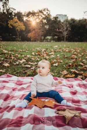 Baby photography - a little girl sits on a checkered blanket at sunset