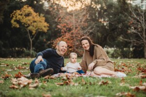 Baby photography - parents sit on a blanket with their baby girl at sunset