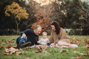 Baby photography - A family sit on a blanket with their baby girl at sunset