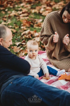 Baby photography - parents sit on a blanket with their baby girl at sunset