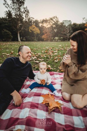 Baby photography - A family sit on a blanket with their baby girl at sunset