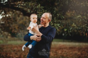 Baby photography - a father cuddles his baby girl in a park