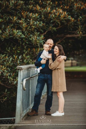 Baby photography - parents stand on a bridge cuddling their baby girl