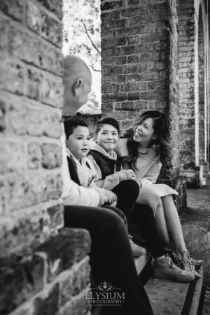 Sydney Family Photographer: parents sit with their sons under a rustic brick arch