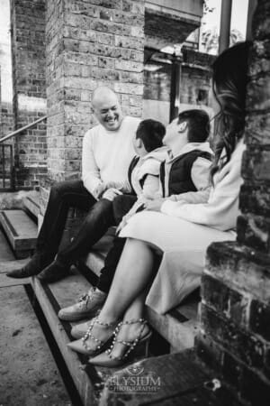 Sydney Family Photographer: parents sit with their sons under a rustic brick arch