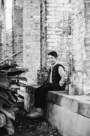 Sydney Family Photographer: a little boy sits against a rustic brick wall