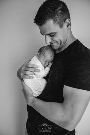 Newborn Photography: a baby boy sleeps in the arms of his dad