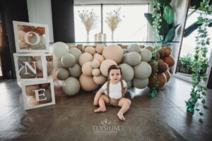 Cake Smash Photographer: a baby boy sits against a balloon wall