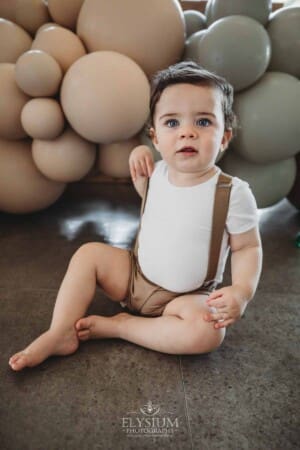 Cake Smash Photographer: a baby boy sits against a balloon wall