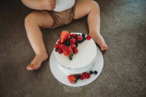 Cake Smash Photographer: a baby boy sits in front of his birthday cake