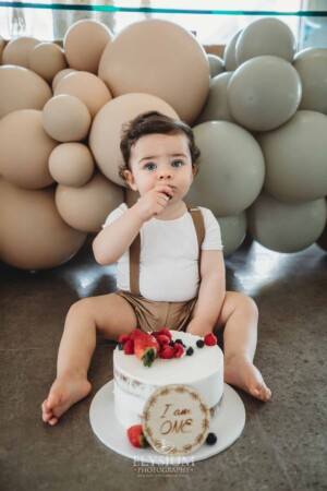 Cake Smash Photographer: a baby boy touches the icing and berries on his cake