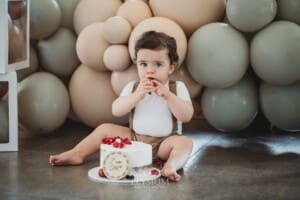 Cake Smash Photographer: a baby boy touches the icing and berries on his cake