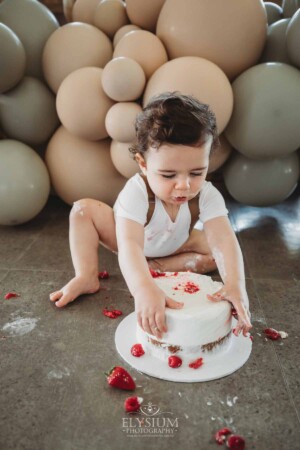 Cake Smash Photographer: a baby boy grabs his cake with both hands