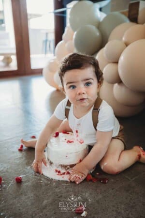 Cake Smash Photographer: a baby boy grabs his cake with both hands