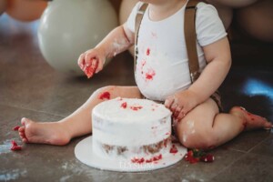 Cake Smash Photographer: a baby boy sits covered in icing