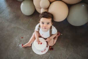 Cake Smash Photographer: a baby boy sits covered in icing and berries
