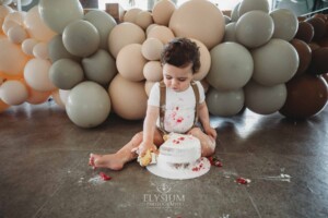 Cake Smash Photographer: a baby boy sits covered in icing and berries