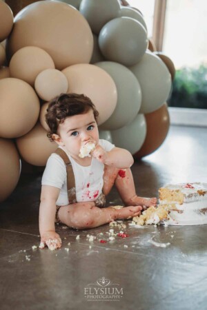 Cake Smash Photographer: a baby boy eats a fistful of cake and icing