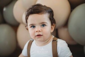 Cake Smash Photographer: a baby boy sits against a balloon wall