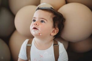 Cake Smash Photographer: a baby boy sits against a balloon wall