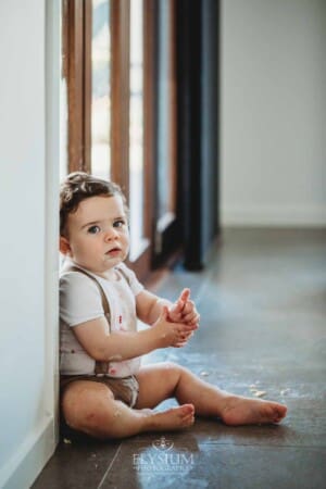 Cake Smash Photographer: a baby boy sits covered in icing