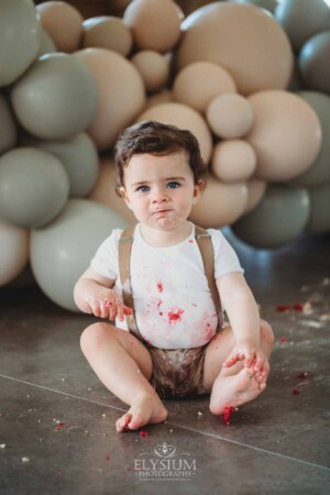 Cake Smash Photographer: a baby boy sits covered in icing