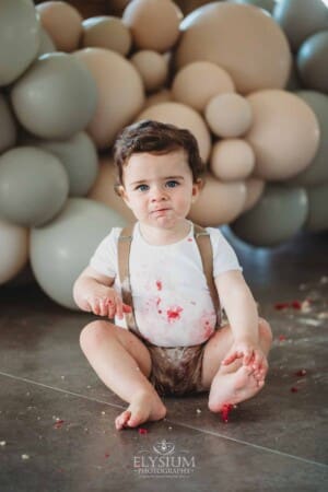 Cake Smash Photographer: a baby boy sits covered in icing