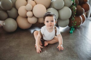 Cake Smash Photographer: a baby boy sits against a balloon wall
