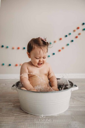 Baby Cake smash Photography: Baby splashing water in a white bath tub