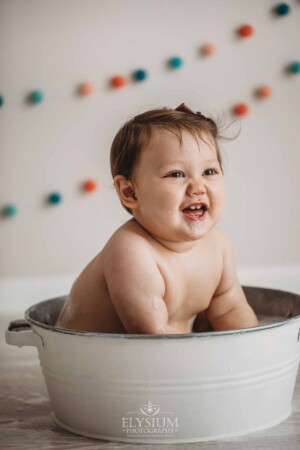 Baby Cake smash Photography: smiley baby sits in a white bath tub