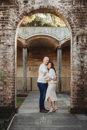 Sydney Family Photographer: a couple cuddle under a rustic brick arch