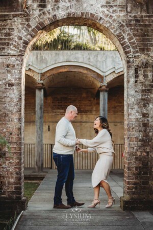 Sydney Family Photographer: a couple laugh holding hands under a rustic brick arch