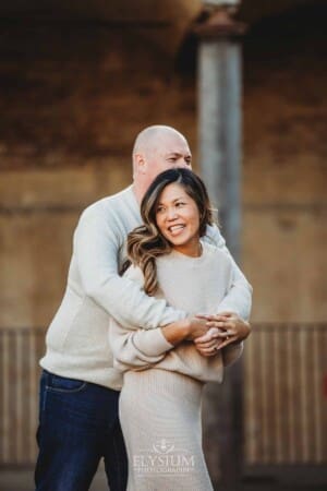 Sydney Family Photographer: a couple cuddle under a rustic brick arch