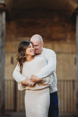 Sydney Family Photographer: a couple cuddle under a rustic brick arch