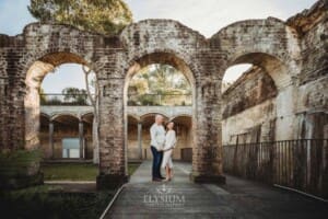 Sydney Family Photographer: a couple cuddle under a rustic brick arch