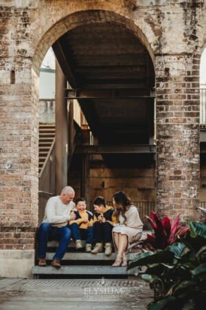 Sydney Family Photographer: parents sit with their sons under a rustic brick arch