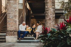 Sydney Family Photographer: parents sit with their sons under a rustic brick arch