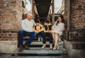 Sydney Family Photographer: parents sit with their sons under a rustic brick arch