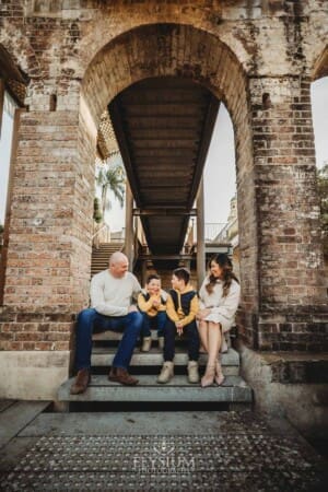 Sydney Family Photographer: parents sit with their sons under a rustic brick arch