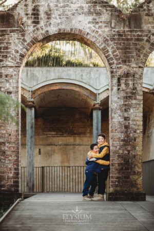 Sydney Family Photographer: brothers stand hugging under a rustic brick arch