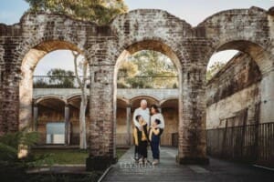 Sydney Family Photographer: parents cuddle their boys under a rustic brick arch