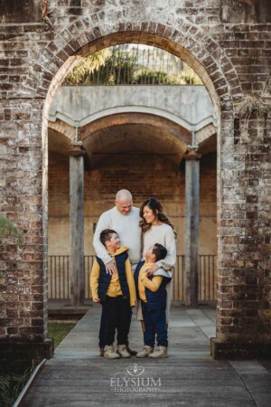 Sydney Family Photographer: parents cuddle their boys under a rustic brick arch