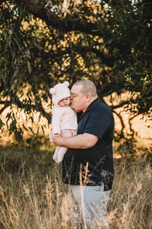 Family Photography: a father kisses his baby girl at sunset
