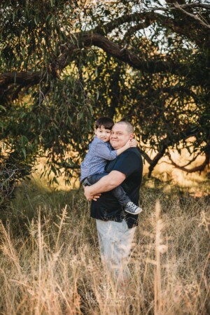 Family Photography: a father cuddles his little boy at sunset