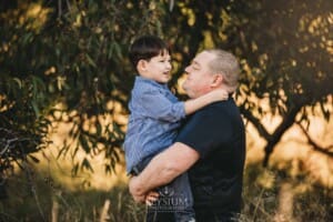 Family Photography: a father cuddles his little boy at sunset