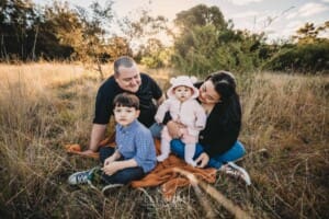 Family Photography: a family sit on a blanket in a grassy field at sunset