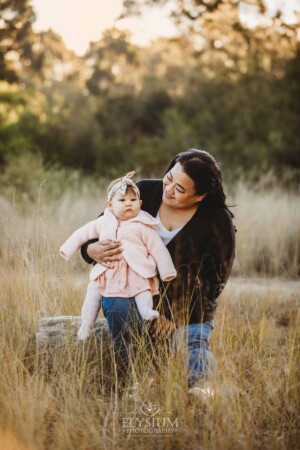 Family Photography: a mother cuddles her baby girl in a grassy field