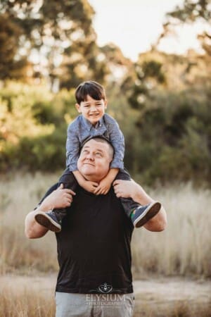 Family Photography: a little boy sits on his dads shoulders at sunset